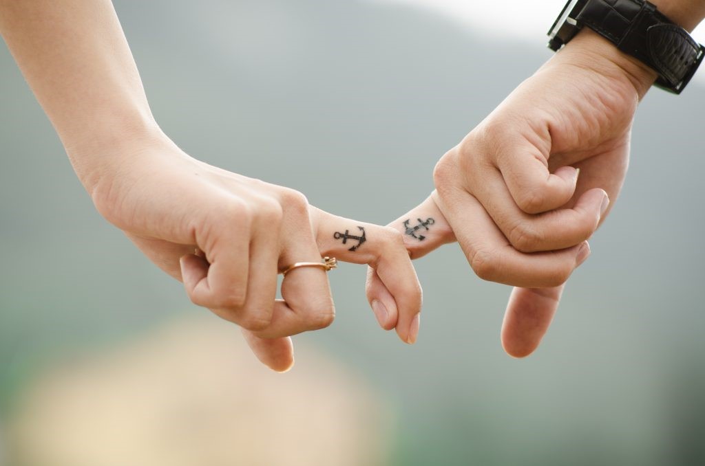 Engagement photograph of a couple holding fingers